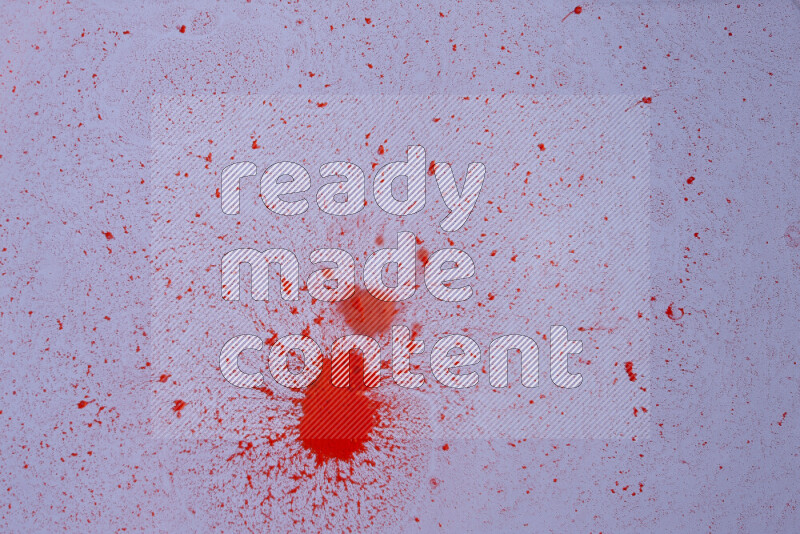 The image captures a dramatic splatter of red paint over a white backdrop