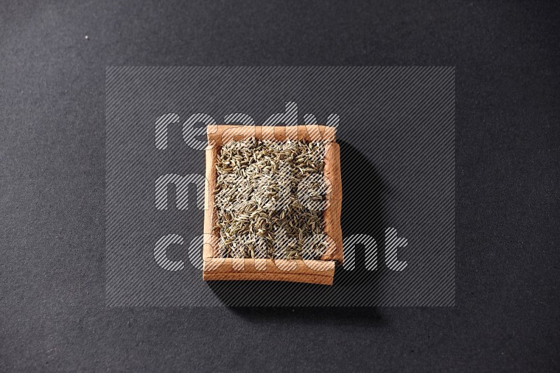 A single square of cinnamon sticks full of cumin on black flooring
