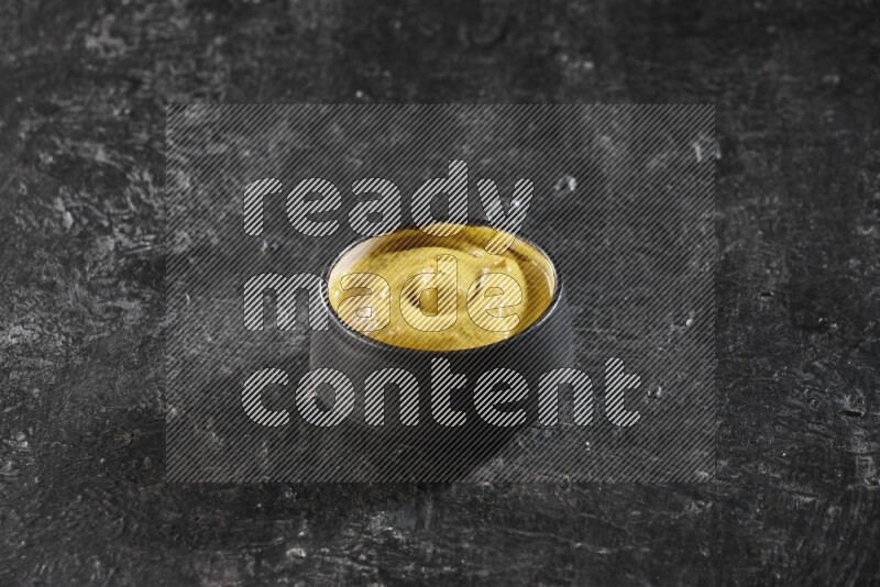 وعاء فخاري أسود ممتلئ بمعجون الخردل علي خلفية سوداء