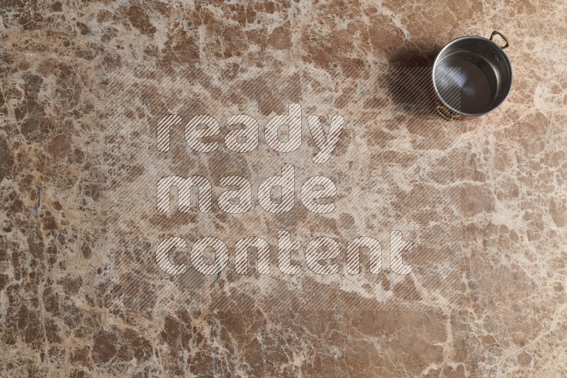 A small copper pot on beige marble background