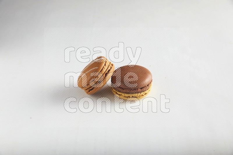 45º Shot of of two assorted Brown Irish Cream, and Yellow, and Brown Chai Latte macarons on white background
