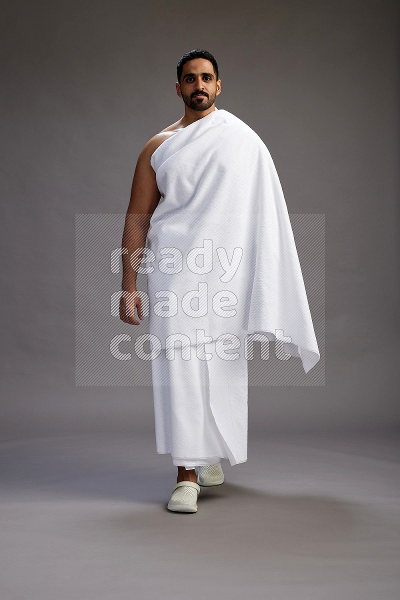 A man wearing Ehram Standing Interacting with the camera on gray background