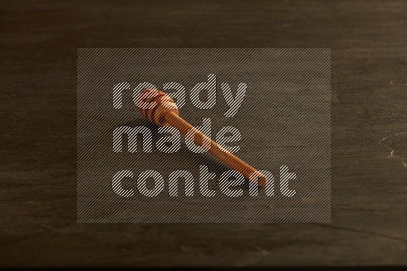 Wooden honey dipper on black slate background