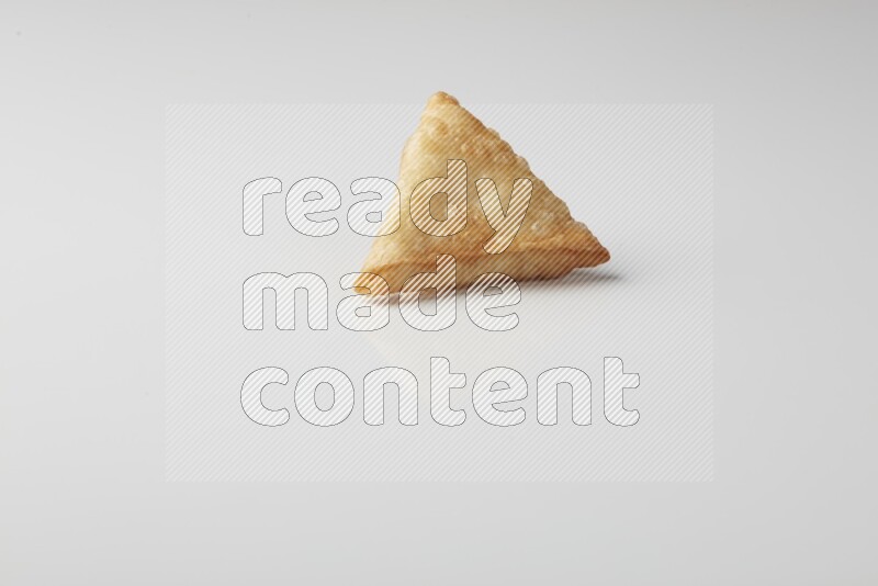 One fried sambosa on a white background