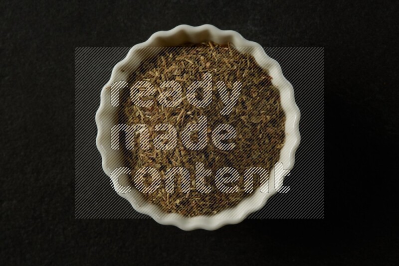 wooden round sauce bowl filled with herbs on grey textured countertop