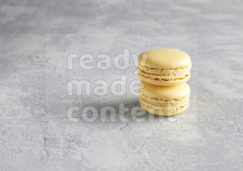 45º Shot of two Yellow Vanilla macarons  on white  marble background