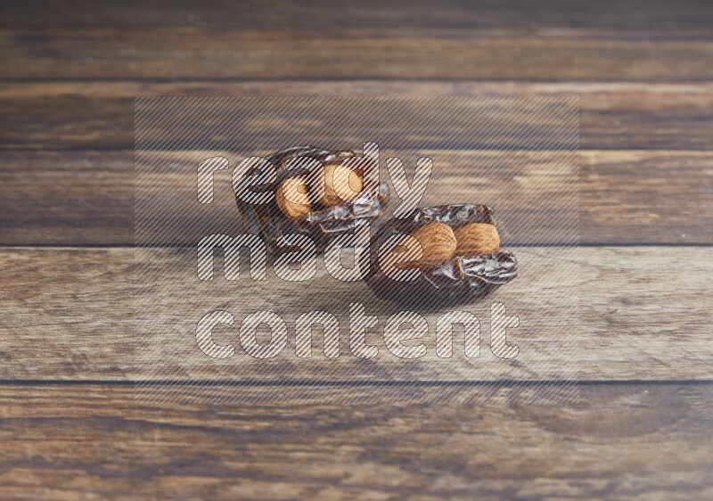 two almond stuffed madjoul dates on a wooden background