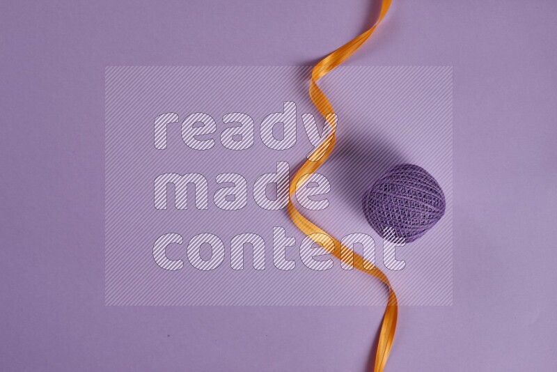 An orange collection of sewing and tailoring tools arranged on a purple background