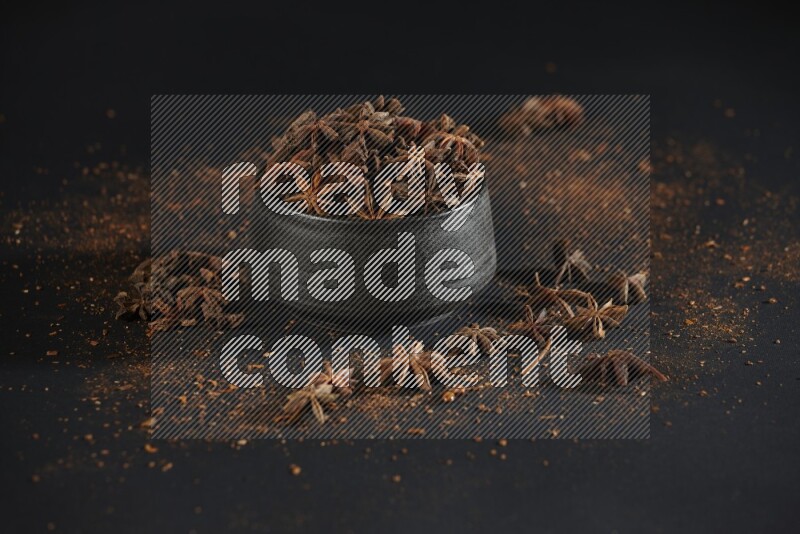 اليانسون النجمي في وعاء أسود مع اليانسون المنثور على خلفية سوداء