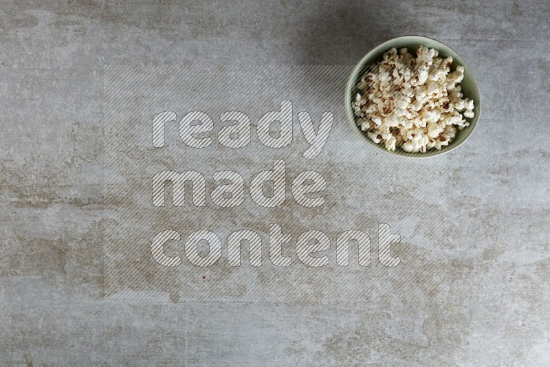 popcorn in green bowl on a grey textured countertop