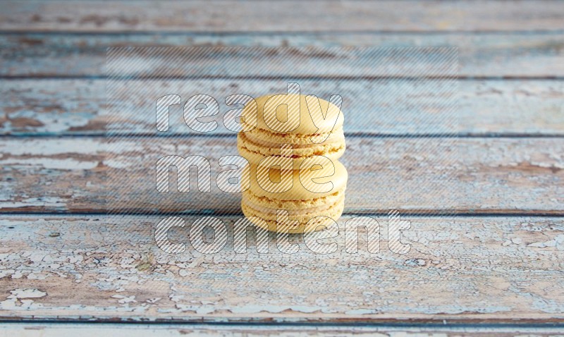 45º Shot of two Yellow Vanilla macarons on a light blue wooden background