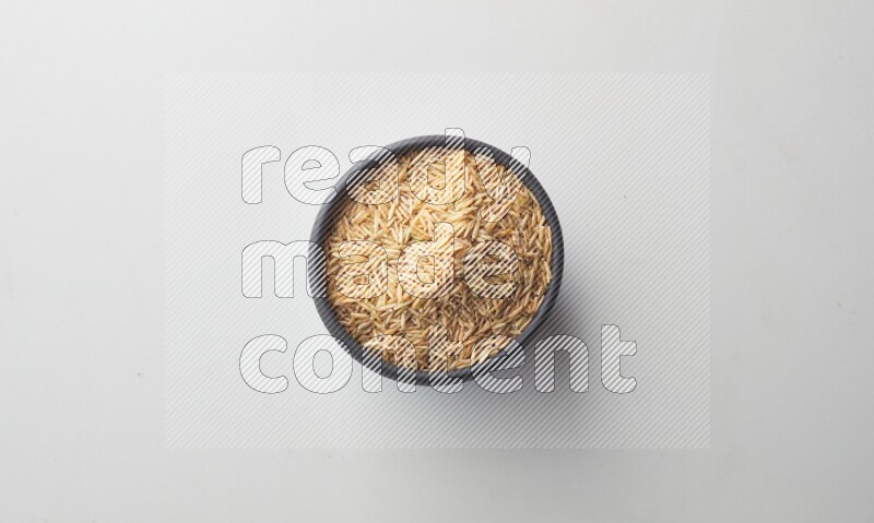 Top-view shot of long grain brown rice in a container on white background