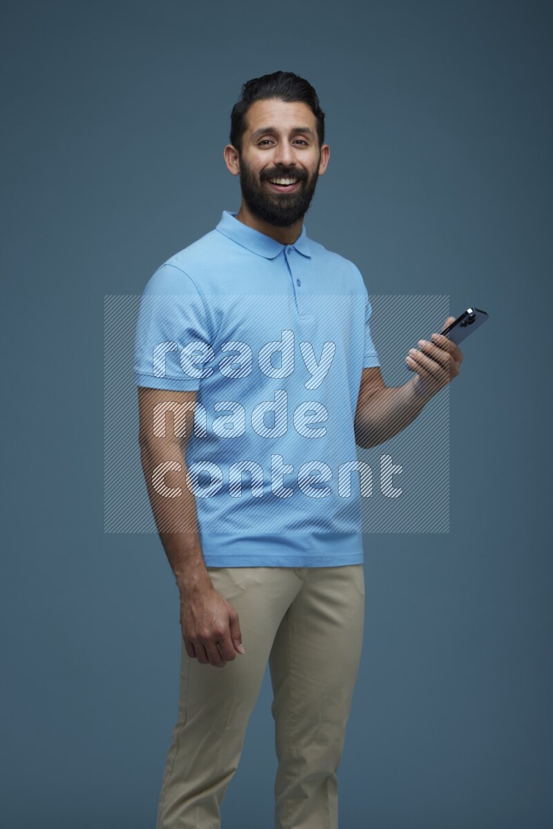 Man posing with a phone in a blue background wearing a Blue shirt