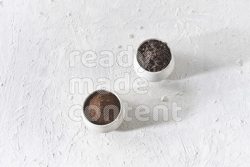 وعاءين من السيراميك بيج اللون، أحدهما مملوء بالقرنفل والآخر مملوء بالبودرة على أرضية بيضاء