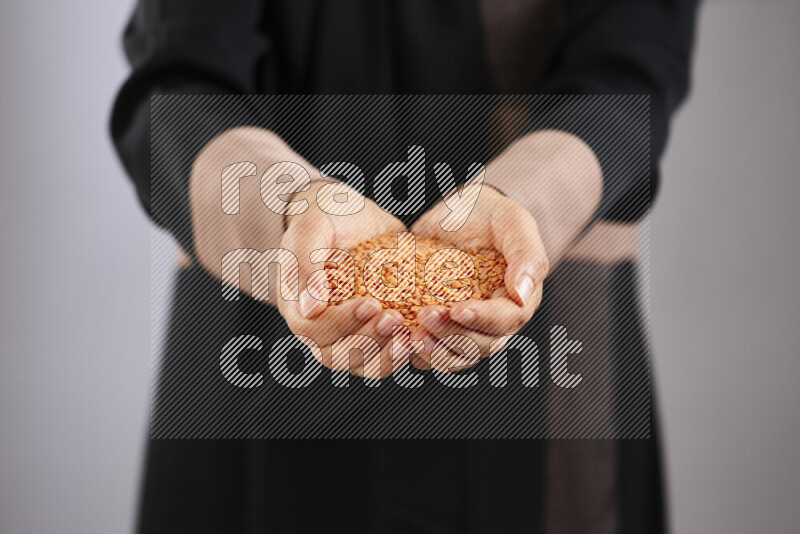 Woman in abaya holding different kinds of legumes in different positions
