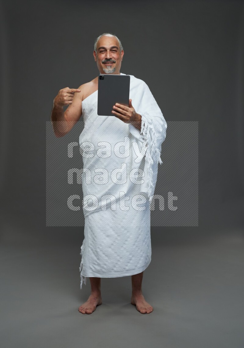 A man wearing Ehram Standing working on tablet on gray background
