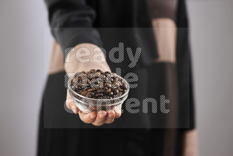 Woman in abaya holding different kinds of coffee beans in different positions
