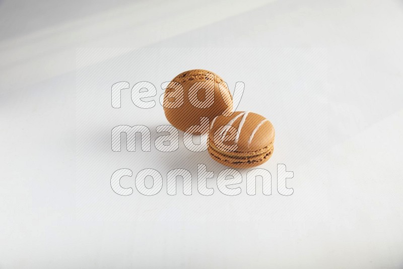 45º Shot of of two assorted Brown Irish Cream, and Brown Maple Taffy macarons  on white background