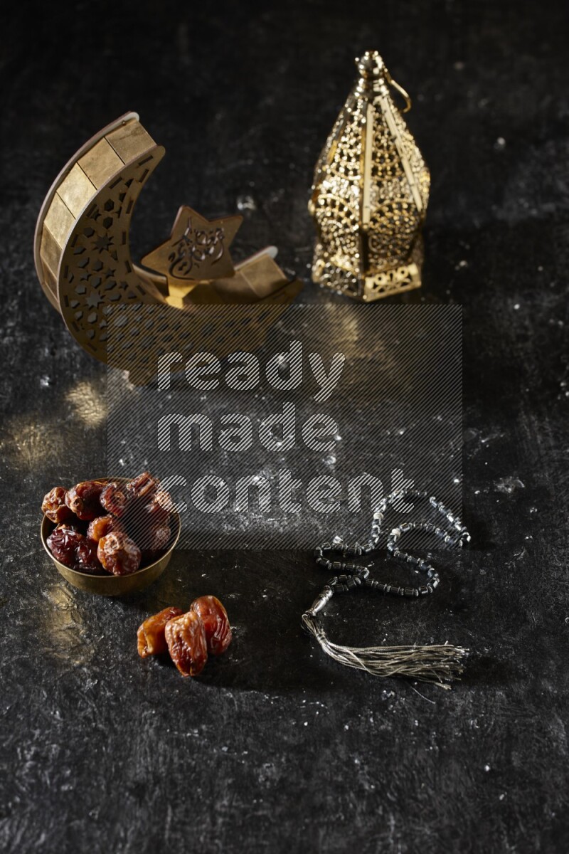 تمر في وعاء معدني مع سبحة بجانب فوانيس ذهبية علي خلفية سوداء