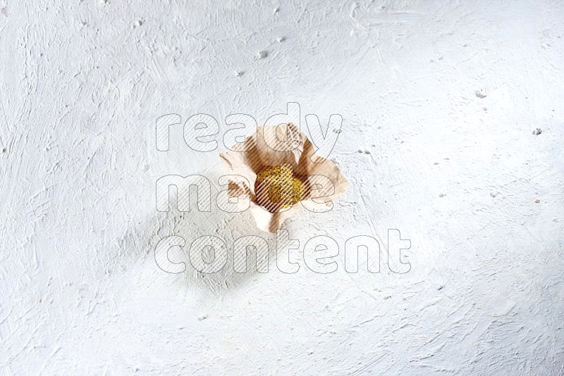 Turmeric powder in a crumpled piece of paper on textured white flooring