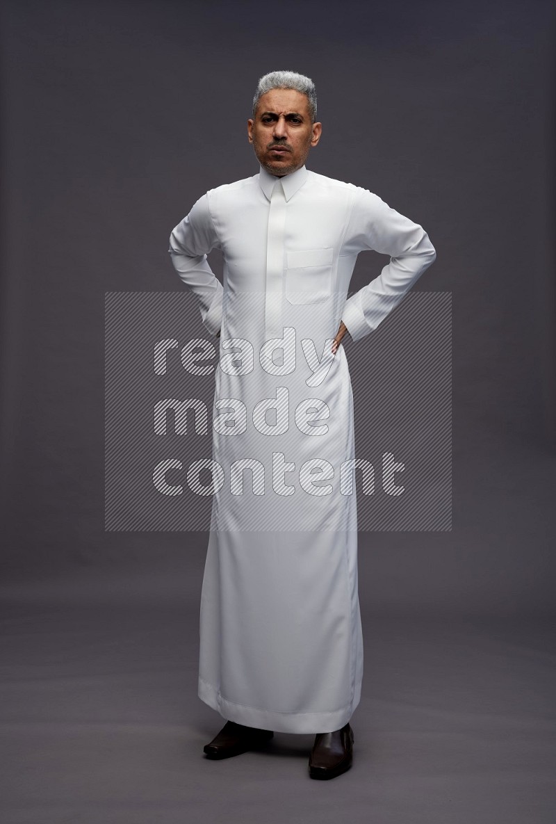 Saudi man wearing thob standing interacting with the camera on gray background