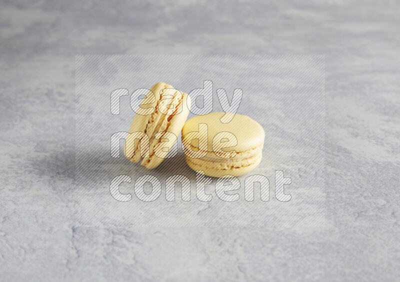 45º Shot of two Yellow Vanilla macarons  on white  marble background