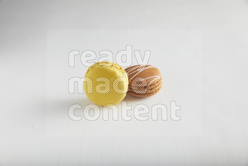 45º Shot of of two assorted Brown Irish Cream, and Yellow Lemon macarons on white background