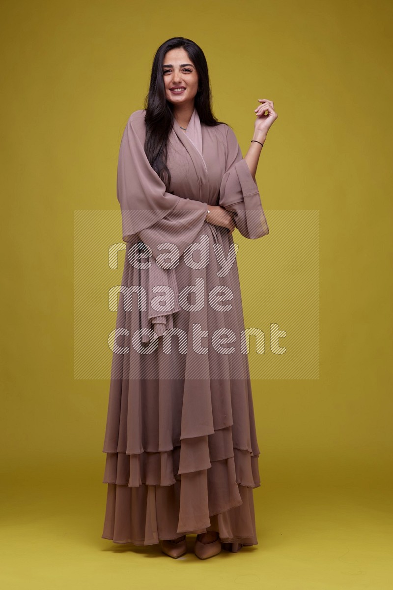 A woman Posing on a Yellow Background wearing Brown Abaya