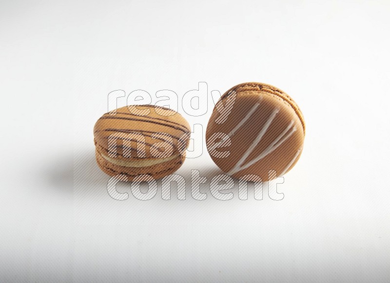 45º Shot of of two assorted Brown Irish Cream, and light brown  Almond Cream macarons on white background