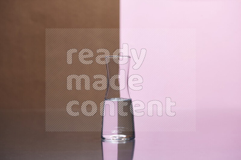 The image features a clear glassware filled with water, set against brown and rose background