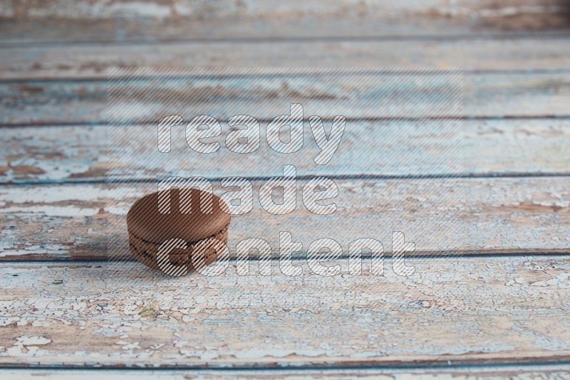 45º Shot of Brown Dark Chocolate macaron on light blue wooden background