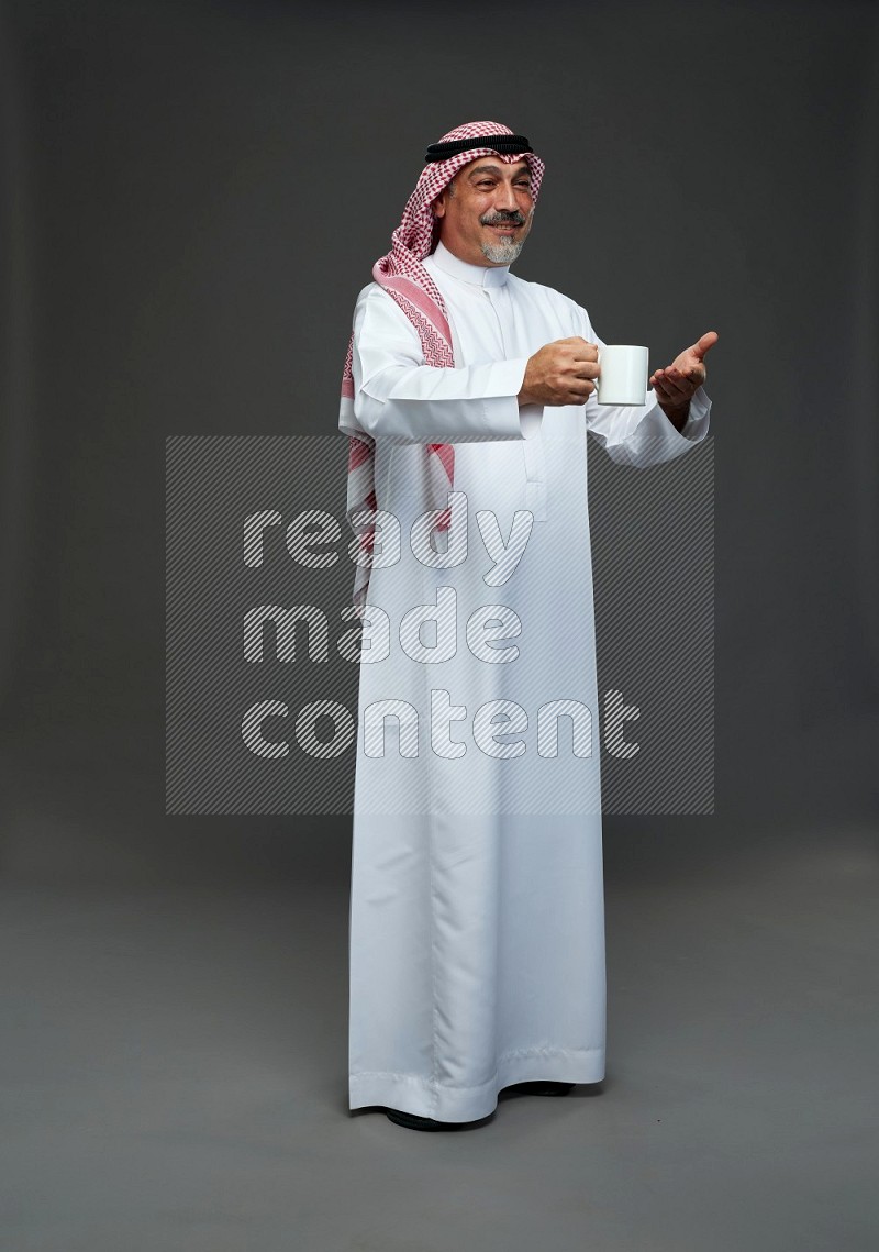 Saudi man with shomag Standing holding mug on gray background