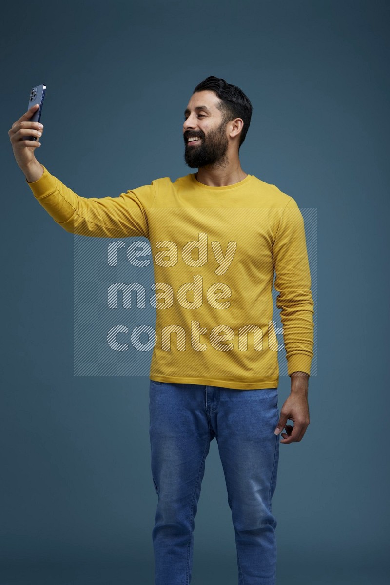 Man Taking a Selfie  in a blue background wearing a yellow shirt