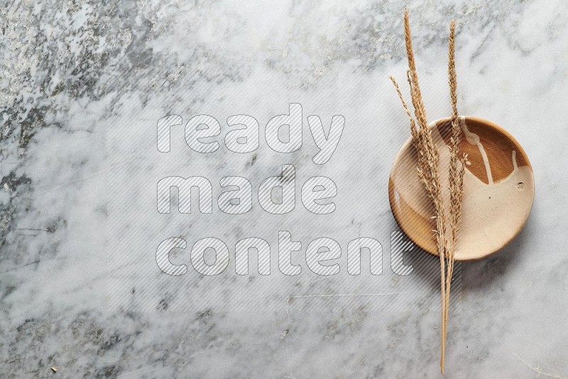 Wheat stalks on Multicolored Pottery Plate on grey marble flooring, Top view