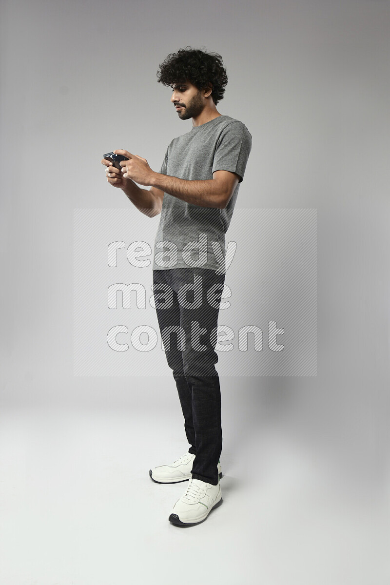 رجل يرتدي ملابس كاجوال يلعب علي الهاتف علي خلفية بيضاء
