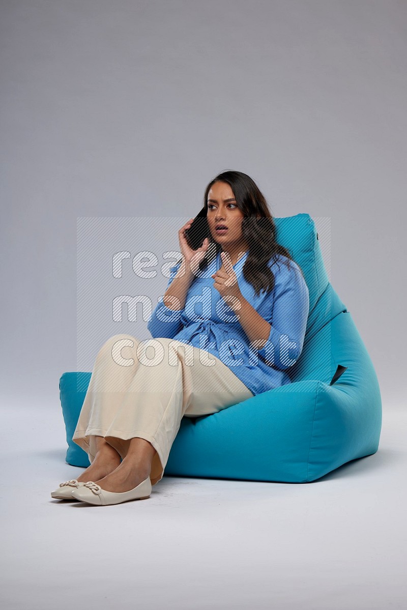 A woman sitting on a blue beanbag and talking on the phone