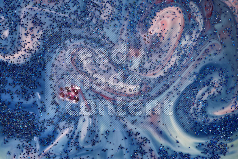 A close-up of sparkling blue glitter scattered on swirling blue and red background