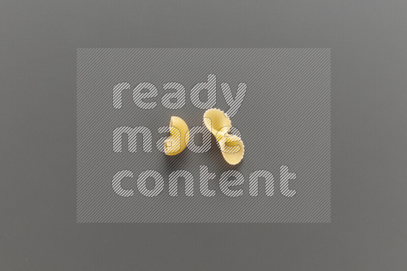 Elbow pasta with other types of pasta on grey background