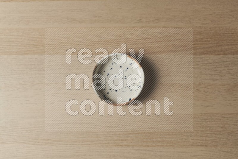 وعاء فخاري متعدد الألوان على خلفية خشبية فاتحة