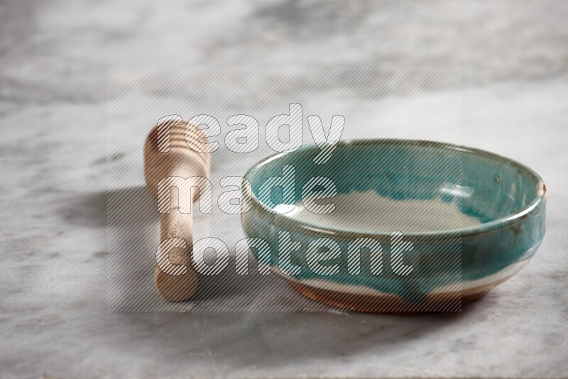 Multicolored pottery bowl with wooden honey dipper on the side on grey marble background