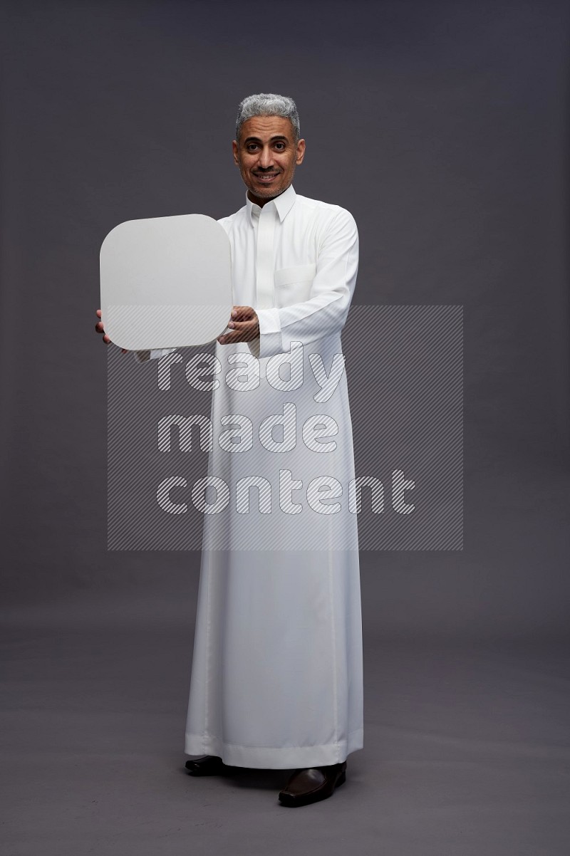 Saudi man wearing thob standing holding social media sign on gray background