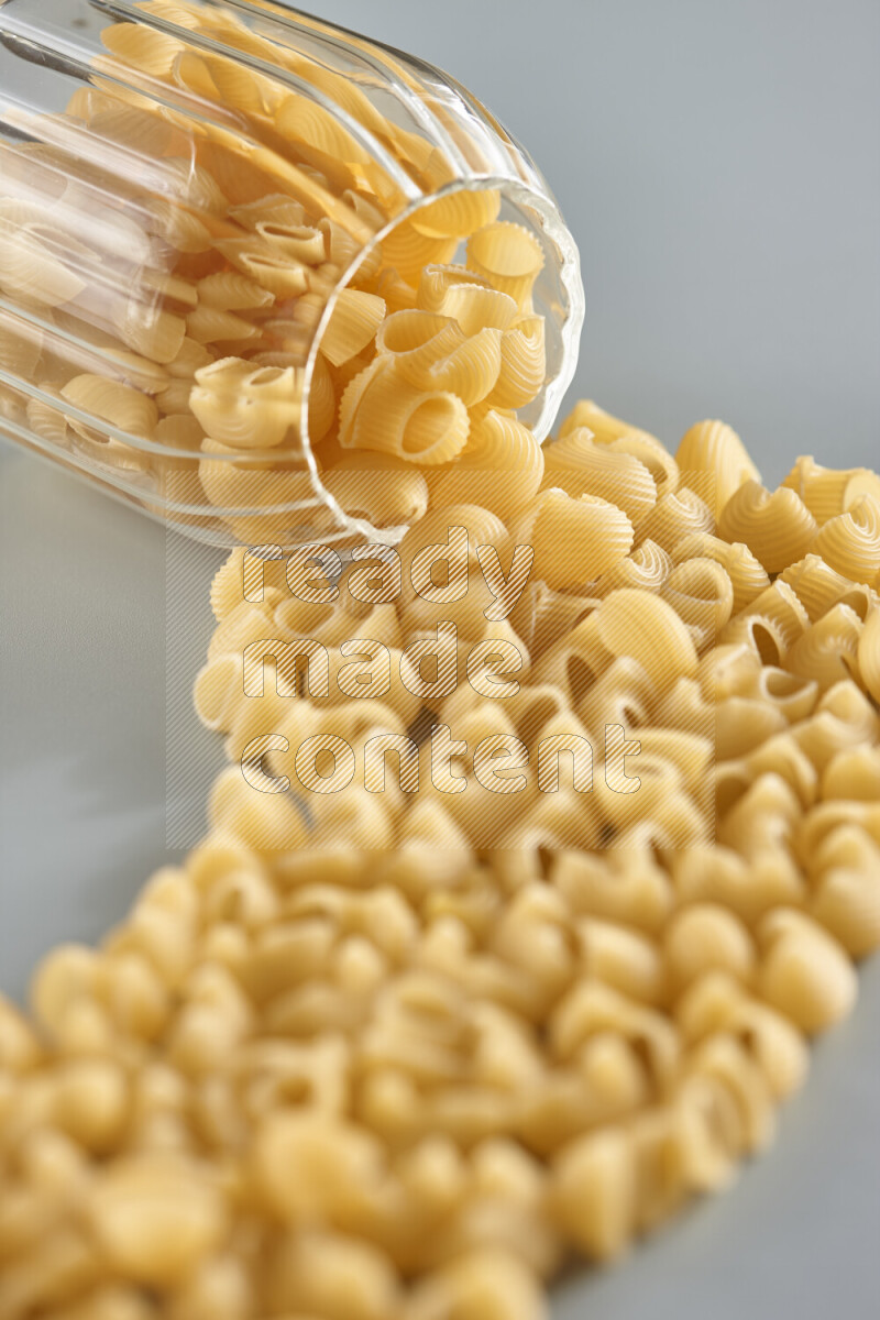 Flipped jar full of raw pasta on light blue background
