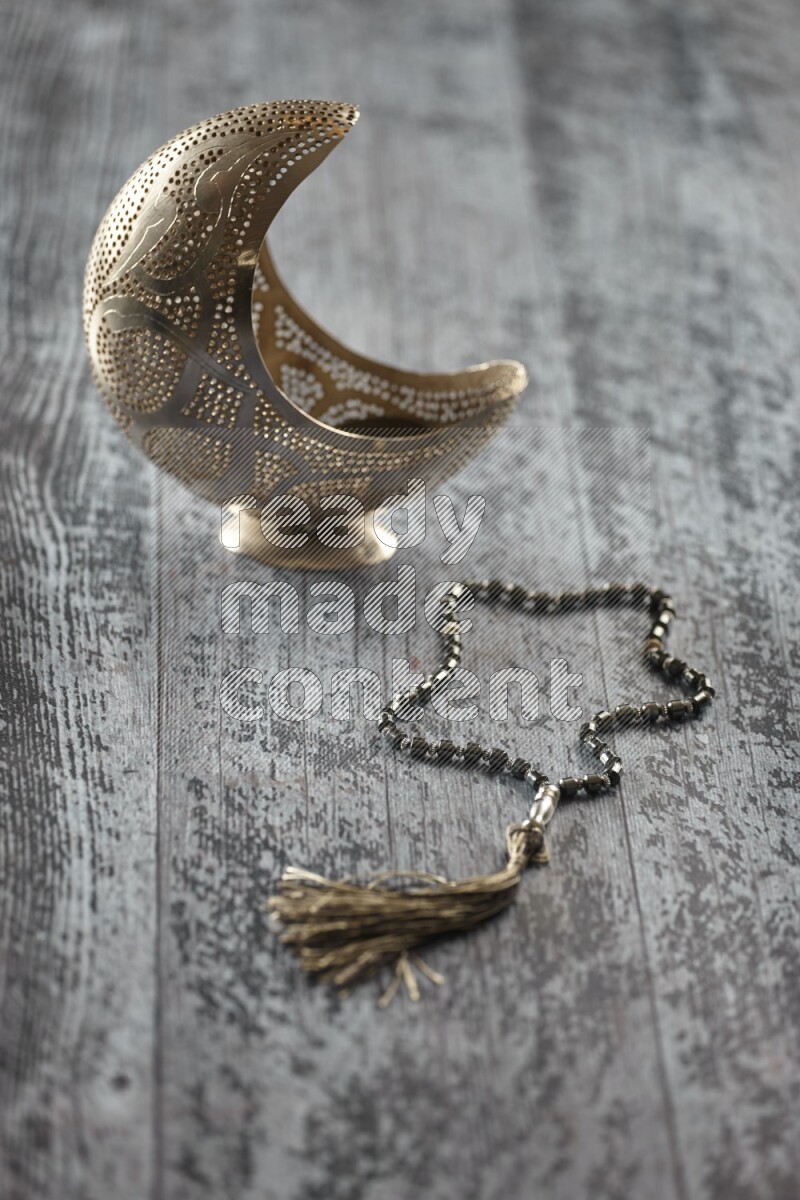 A silver lantern with different drinks, dates, nuts, prayer beads and quran on grey wooden background