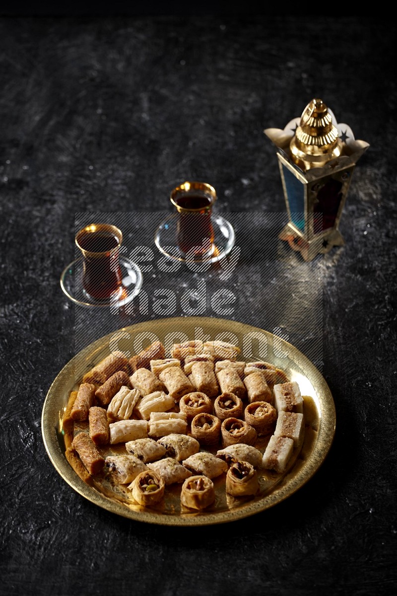 Oriental desserts with tea and a metal lantern in a dark setup