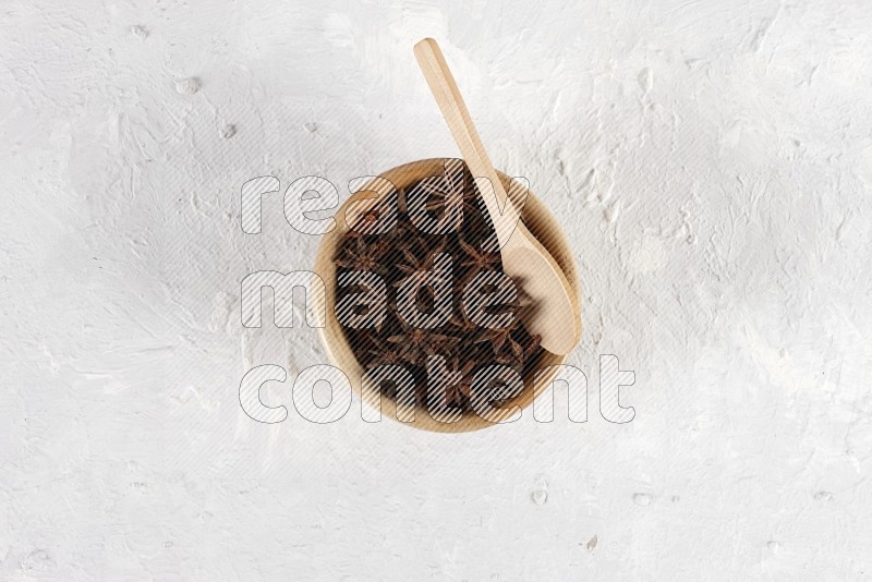 يانسون نجمي في وعاء خشبي به ملعقة خشبية على خلفية بيضاء
