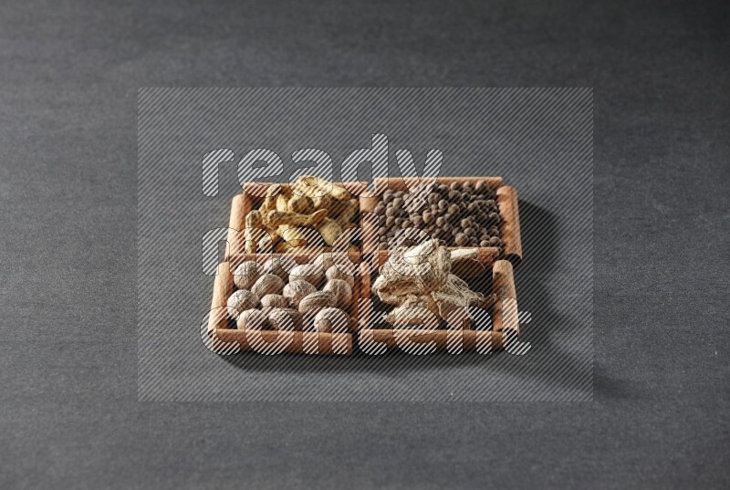 4 squares of cinnamon sticks full of turmeric fingers, allspice, dried ginger and nutmegs on black flooring