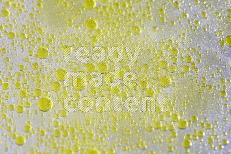 Close-ups of abstract yellow watercolor drops on oil Surface on white background