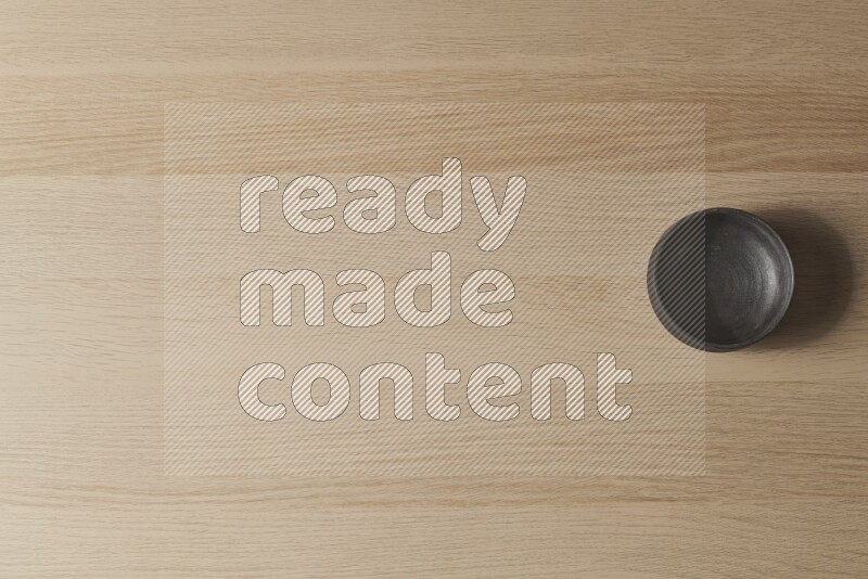 وعاء فخاري أسود على خلفية خشبية فاتحة