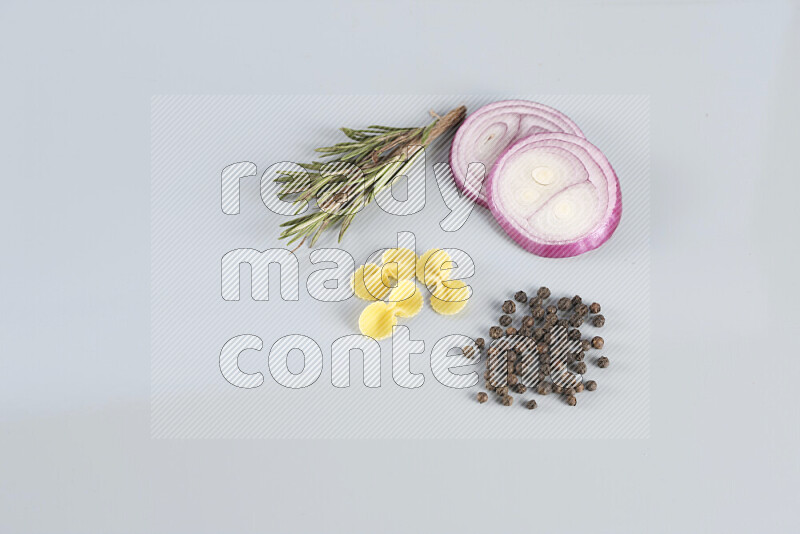 Raw pasta with different ingredients such as cherry tomatoes, garlic, onions, red chilis, black pepper, white pepper, bay laurel leaves, rosemary, cardamom and mushrooms on light blue background