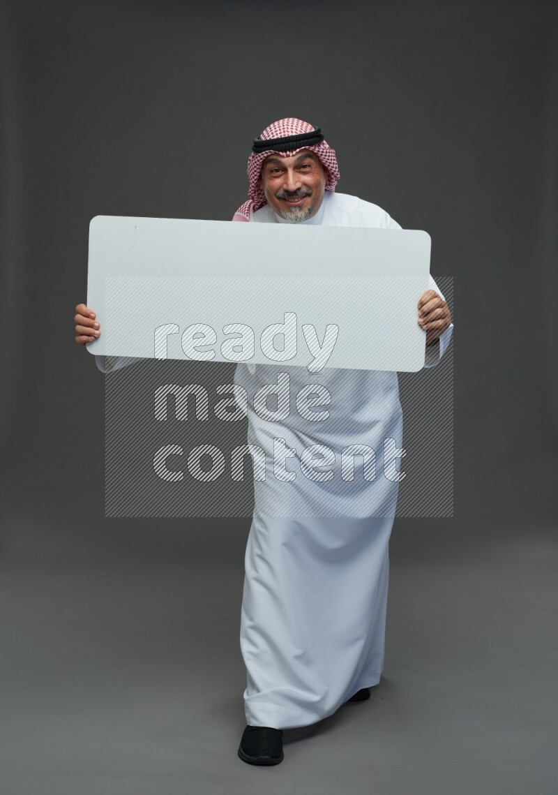 Saudi man with shomag Standing holding social media sing on gray background